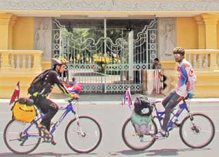 Nepalese cyclists Biresh Prasad Dahal (right) and Babin Basnet ride past the Royal Palace in Phnom Penh